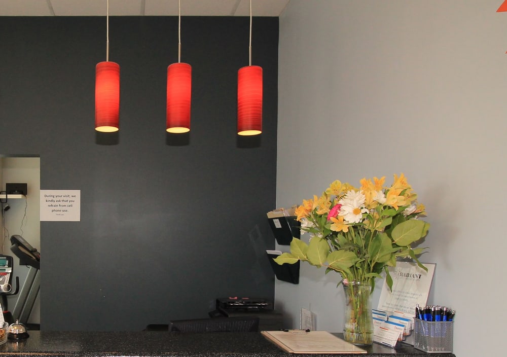 The three red pendant lamps above the front desk at Radiant Physiotherapy